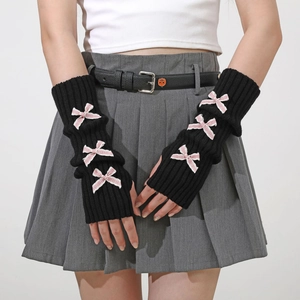 Detail of black knitted arm warmers with pink bows and ribbed cuffs in Y2K style