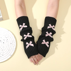 Detail of black knit arm warmers with cute pink bow accents and ribbed texture