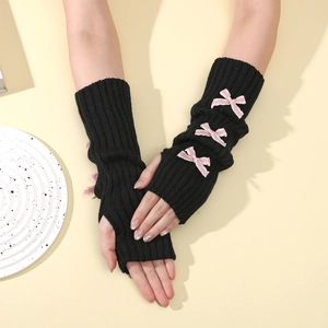 Detail of black knitted arm warmer featuring three pink satin bows and thumb hole design