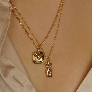 Dubbellaagse gouden ketting met artistiek vrouwelijk lichaam hanger en figaro-schakel