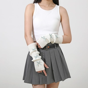 Close-up of white knitted arm warmers with blue bow accents and fingerless design
