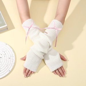 Texture de tricot détaillée des mitaines blanches ornées de nœuds en ruban rose