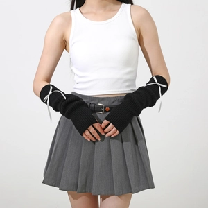 Détail de mitaines en tricot noir ornées de nœuds en ruban blanc et poignets côtelés