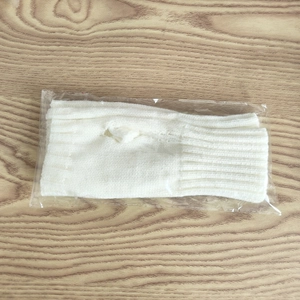 Mitaines tricotées blanches avec trou pour le pouce dans un emballage plastique