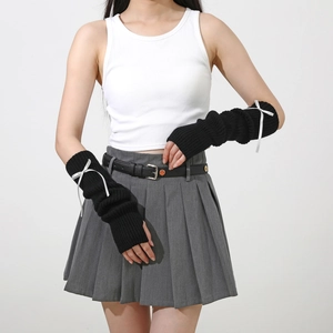 Détail de mitaines en tricot noir à rayures avec nœuds en satin blanc sur mannequin