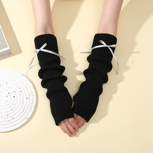 Gros plan de mitaines en tricot noir avec texture côtelée et détails de nœuds en soie blanche