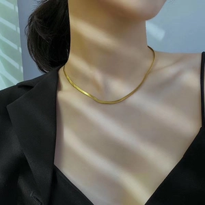 Collar de cadena de serpiente plana dorada minimalista usado por modelo con sombras luz
