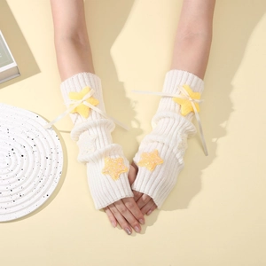 Detail of plush yellow star and ribbon bow on cream cable knit Y2K arm warmers