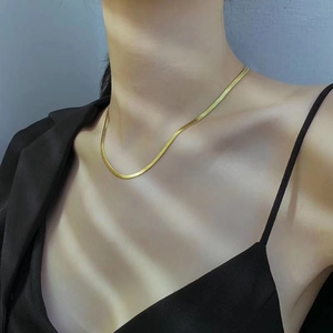 Primer plano de un collar de cadena de serpiente dorada sobre modelo con luces y sombras