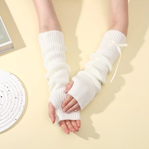 Gros plan détaillé de mitaines en tricot crème avec texture côtelée et nœud en ruban