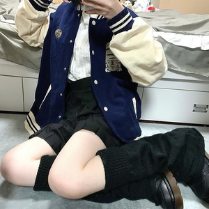 Detailed view of dark blue varsity jacket with tiger embroidery and pleated skirt