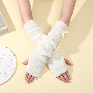 Détail de mitaines en tricot crème avec un nœud en ruban et une texture côtelée