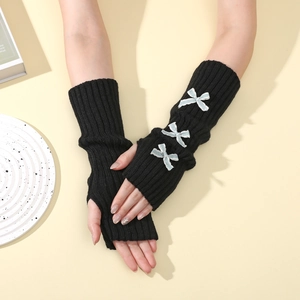 Detail of black knit arm warmers featuring white lace bows and thumb hole design