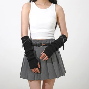 Gros plan de mitaines en tricot noir avec nœud de style Y2K portées par un mannequin