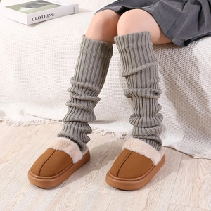 Gros plan sur des jambières en maille grise avec des chaussons en peluche marron douillets