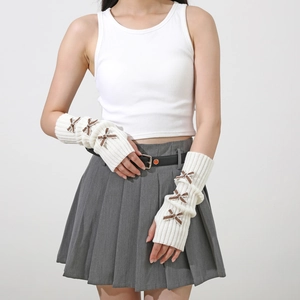 Detailed knit texture of white fingerless arm warmers with brown ribbon bow accents