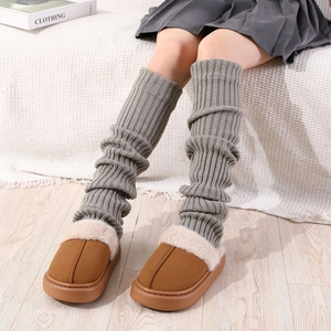 Gros plan de jambières en tricot gris épais avec des chaussons en daim marron et fourrure