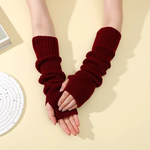 Close-up of burgundy knit arm warmers with thumb holes and ribbed texture on the sleeves