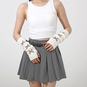 Close-up of white knit arm warmers with brown ribbon bows and ribbed cuffs