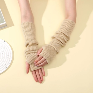 Detail of beige knit arm warmers with thumb holes and thick ribbed texture for winter