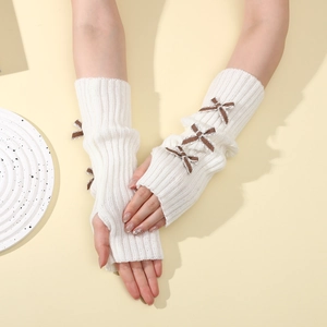 Close-up of cream-white knit fingerless gloves featuring three brown plaid bows on the arm