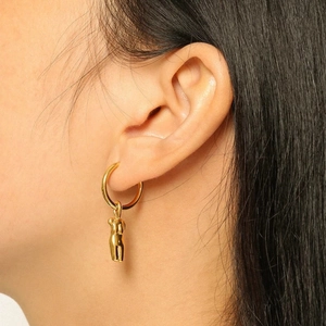 Détail d'une boucle d'oreille en plaqué or 18k avec pendentif corps féminin