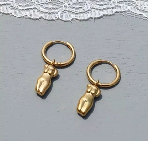 Détail de boucles d'oreilles créoles en acier doré 18 carats avec pendentifs torse