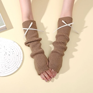 Détail de mitaines en maille marron avec nœud blanc et trou pour le pouce
