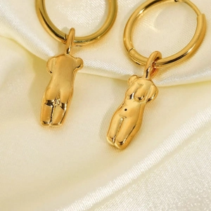 Gros plan de boucles d'oreilles pendentifs torse doré sur tissu en soie beige