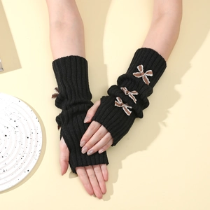 Detail of black knit fingerless arm warmers featuring brown checkered bow embellishments