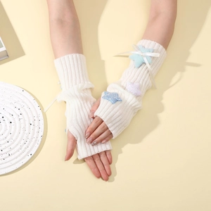 Close-up of knit arm warmers with plush colorful stars and decorative white ribbons