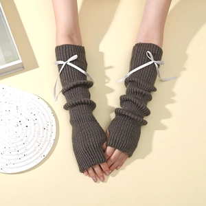 Détail de mitaines en tricot marron foncé avec un petit nœud en satin blanc chic