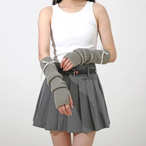 Détail du tricot des mitaines grises avec décoration de nœuds en ruban blanc doux
