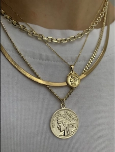 Nahaufnahme von vierlagigen 18k vergoldeten Edelstahl-Münzhalsketten auf weißem T-Shirt
