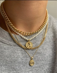 Detail von mehrlagigen Goldketten mit groben Gliedern, Perlen und Münzanhängern mit Relief