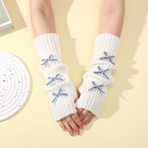 Close-up of white ribbed knit arm warmers with blue checkered bows and fingerless design