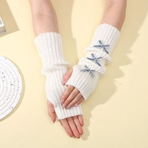 Detail of white rib-knit fingerless gloves with blue plaid bows for winter warmth