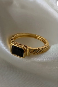 Primer plano de un anillo vintage chapado en oro con piedra negra rectangular y espirales