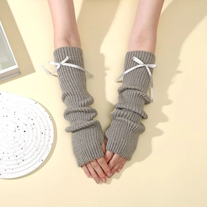 Détail de mitaines en tricot gris avec nœuds en soie blanche au style hivernal doux