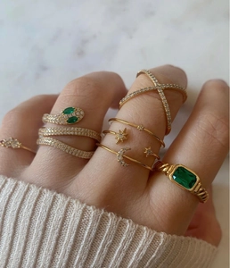 Primer plano de anillo de serpiente dorado y anillo de esmeralda con punto blanco
