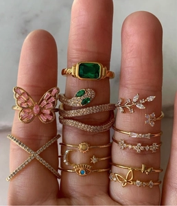 Primer plano de anillos apilables bañados en oro 18k con piedras y mariposa