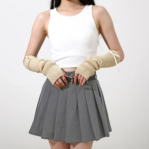 Détail des mitaines en tricot beige avec de délicats nœuds en ruban blanc aux poignets