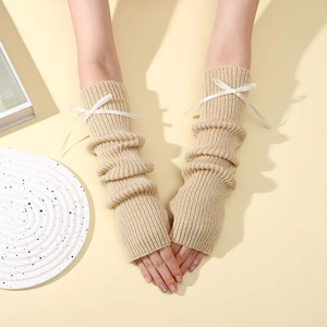 Gros plan de mitaines en tricot beige avec nœuds en ruban blanc et détails de texture