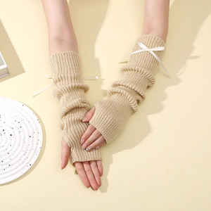 Détail des mitaines en maille beige avec texture côtelée et petit nœud élégant