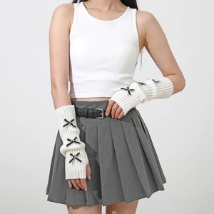 Close-up of white knit arm warmers with black ribbon bows and fingerless design