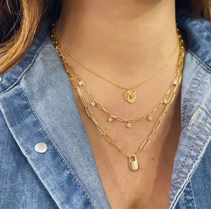 Detailweergave van gelaagde 18k vergulde kettingen met tijgerkop- en slot hangers