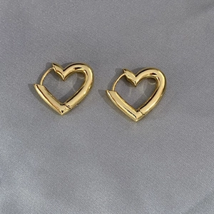 Boucles d'oreilles cœur en or 18k polies sur un élégant fond en soie grise