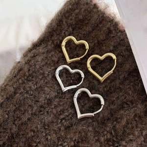 Créoles minimalistes en forme de cœur dorées et argentées sur un fond en tricot doux