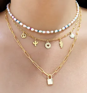 Detail van de drielaagse gouden ketting met hangslotje, parels en diverse bedels