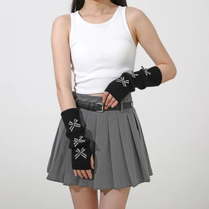 Detail of black knit arm warmers with white bows showing rib-knit texture and Y2K style